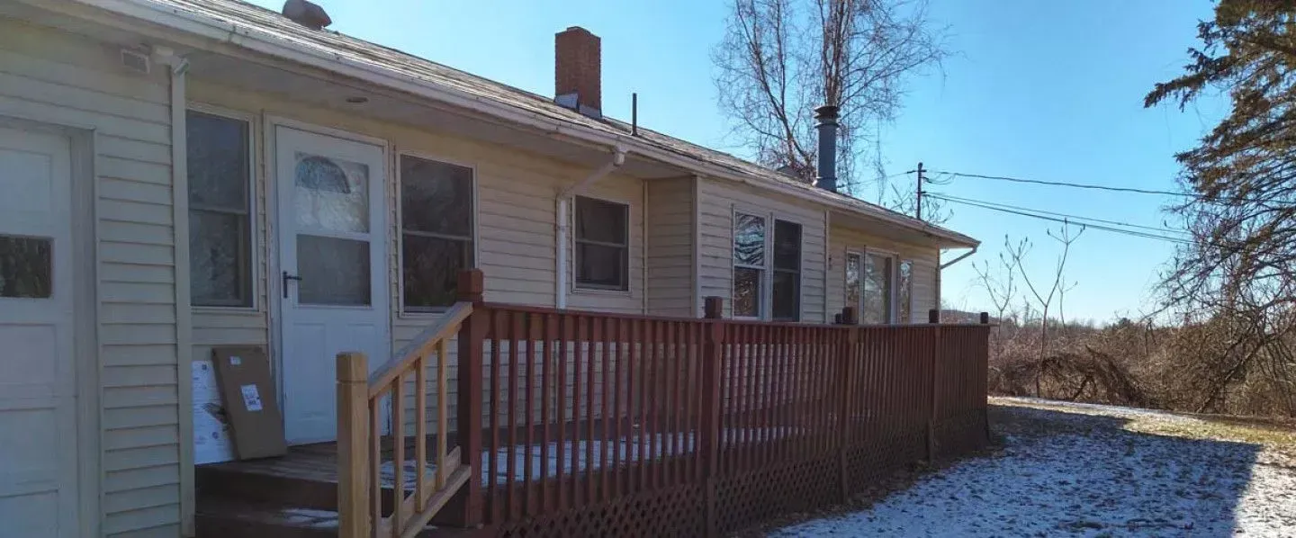 A house with a wooden fence and stairs in front of it.