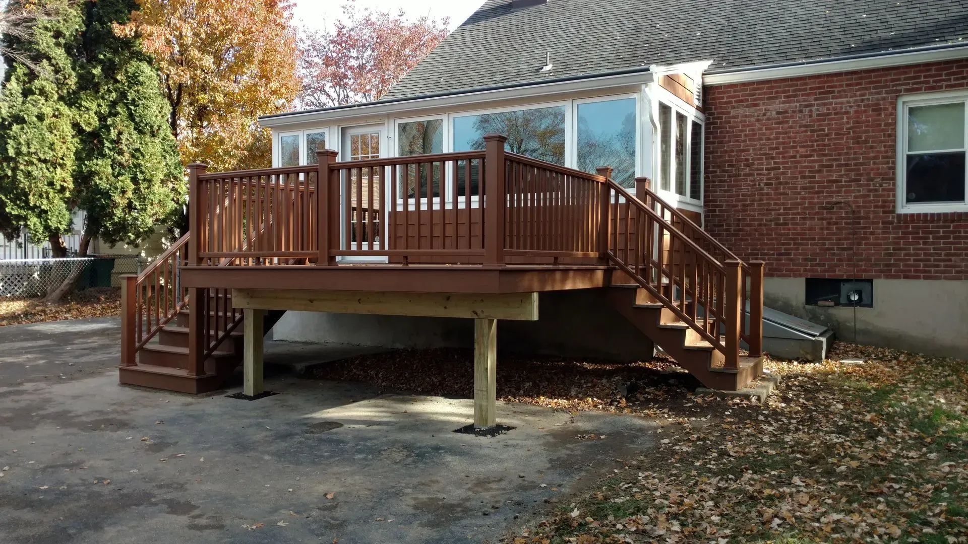 A wooden deck with stairs is in front of a brick house.
