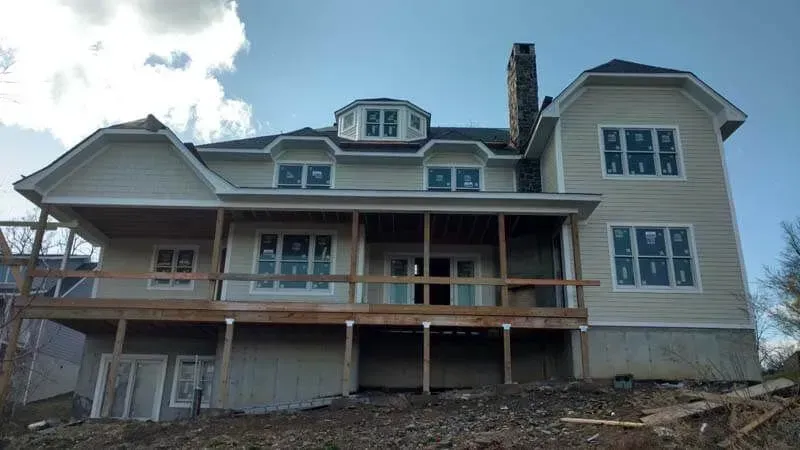 A large house is being built on a hill with a large deck.