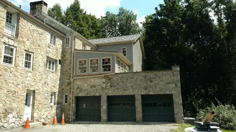 A large stone house with three garage doors in front of it