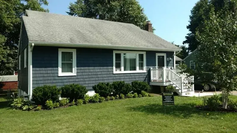 A blue house with white trim and a gray roof