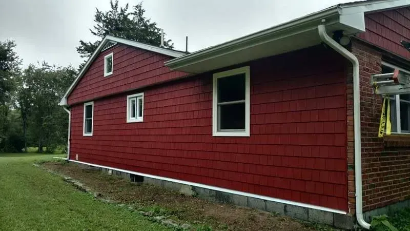 The side of a red house with white trim and windows.