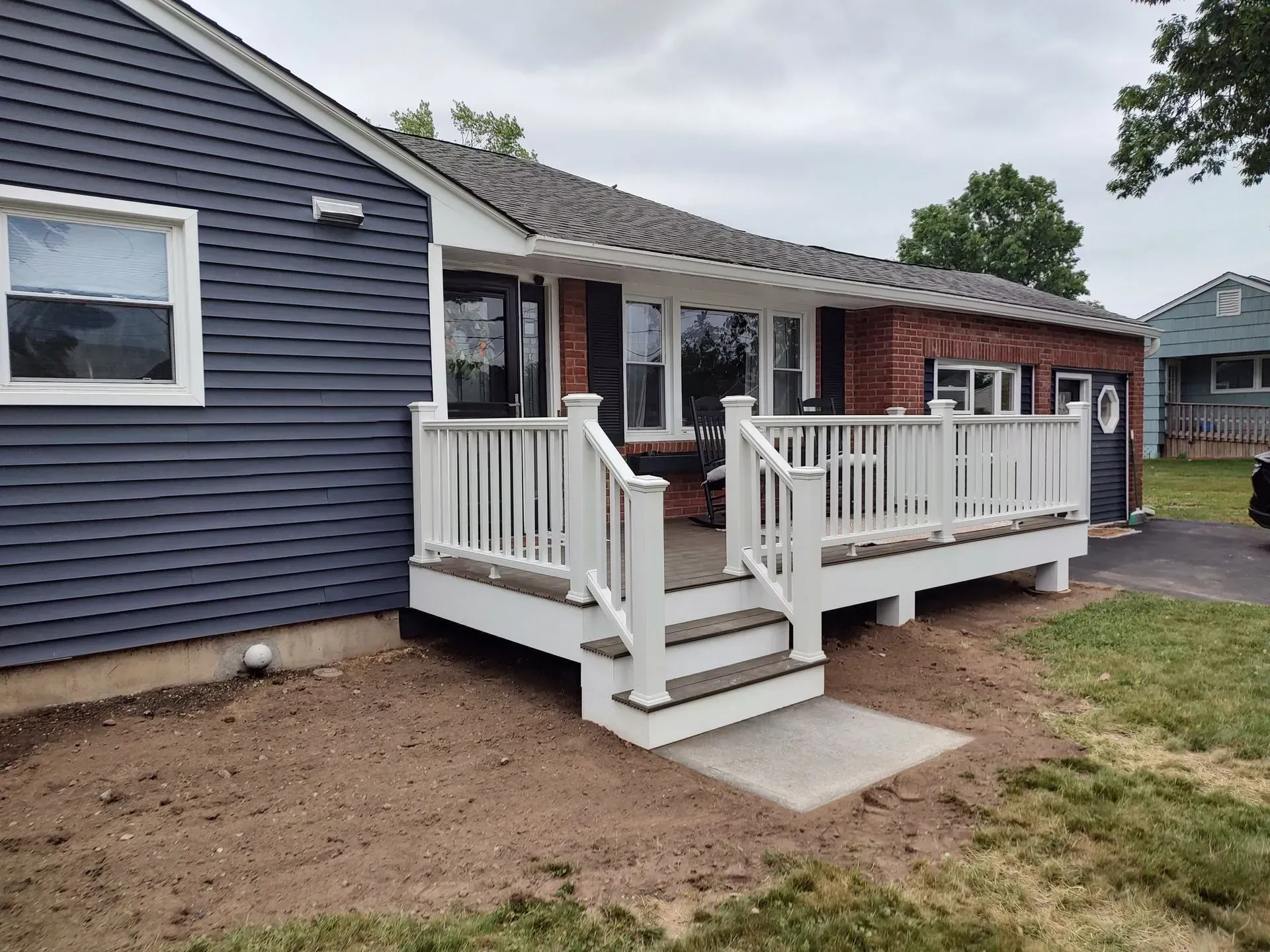 A blue house with a white deck in front of it.