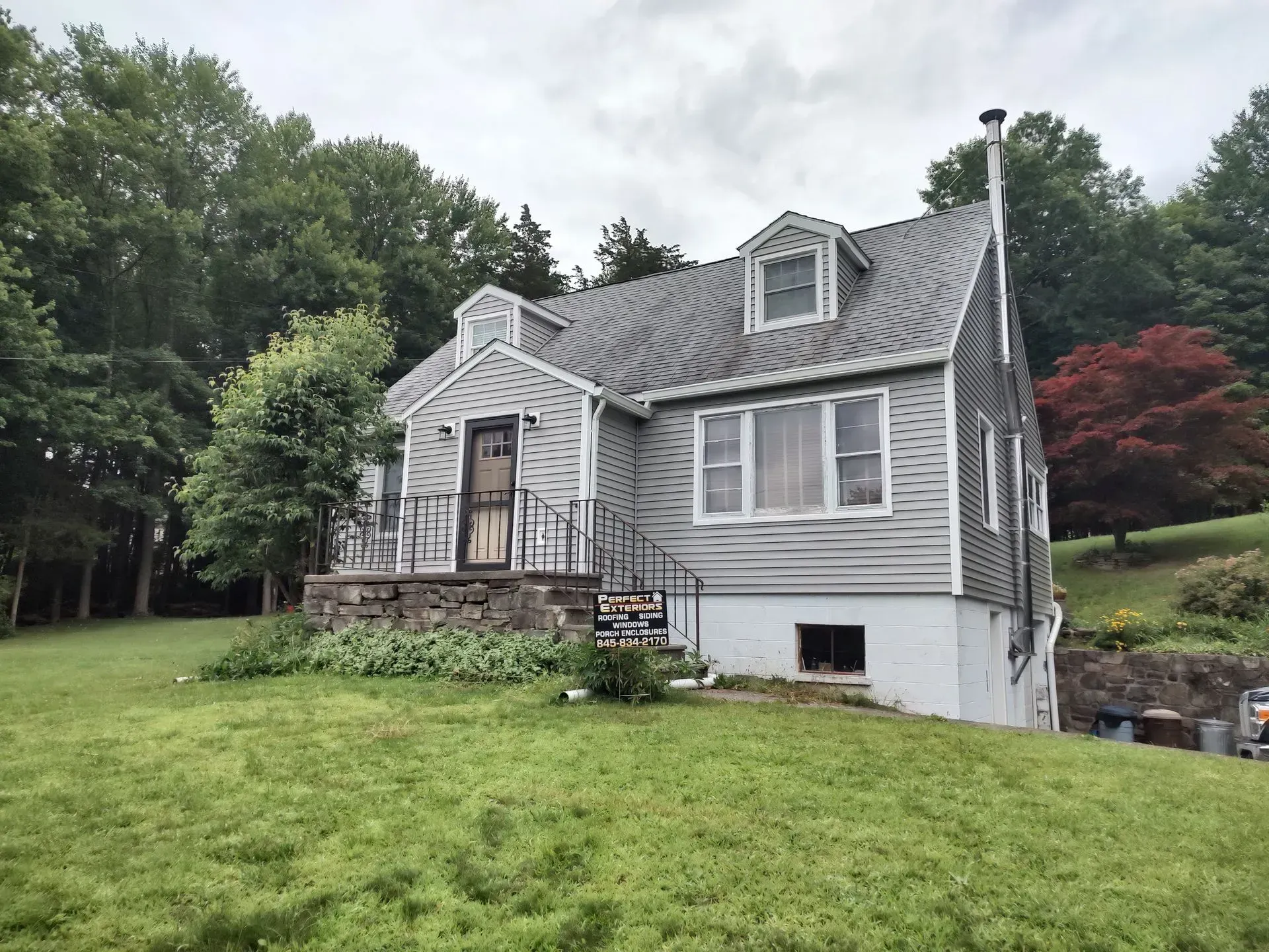 A house is sitting on top of a lush green hillside surrounded by trees