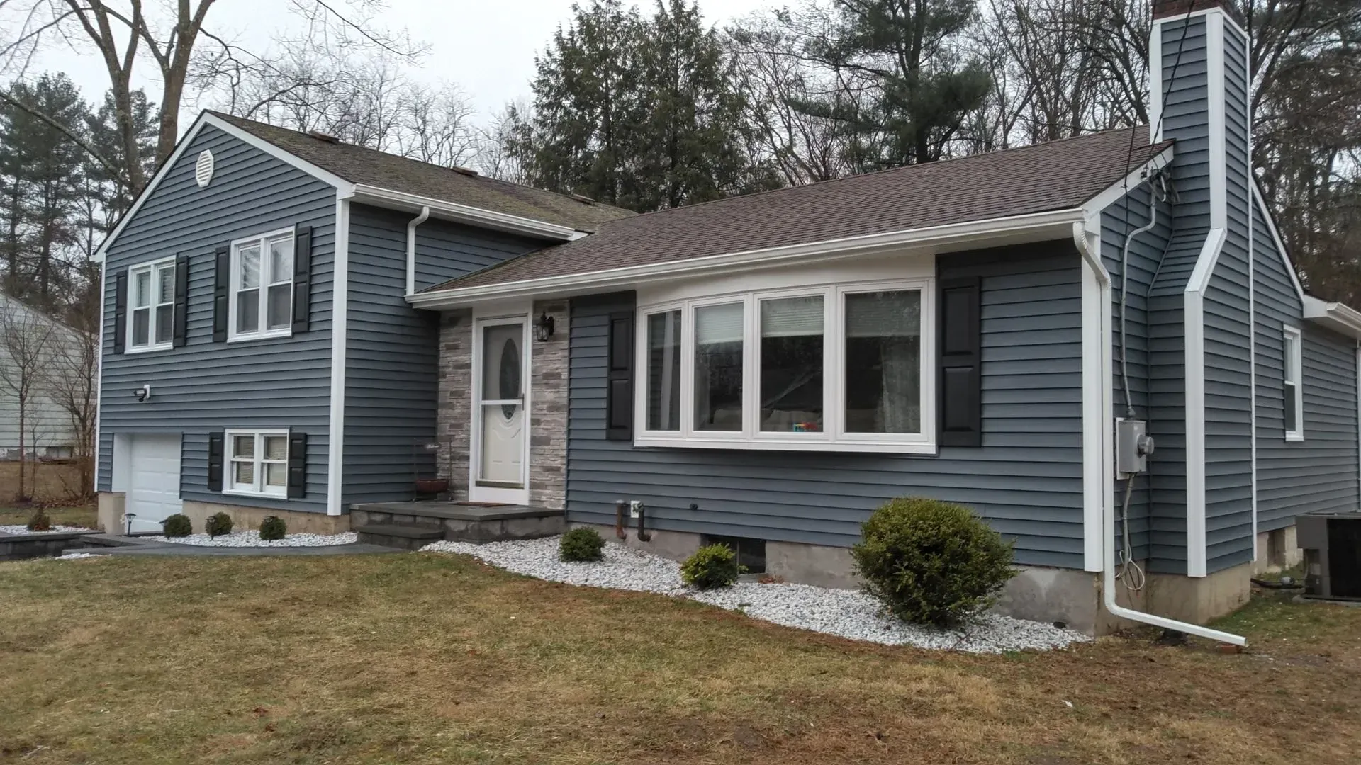 A blue house with black shutters and a large window