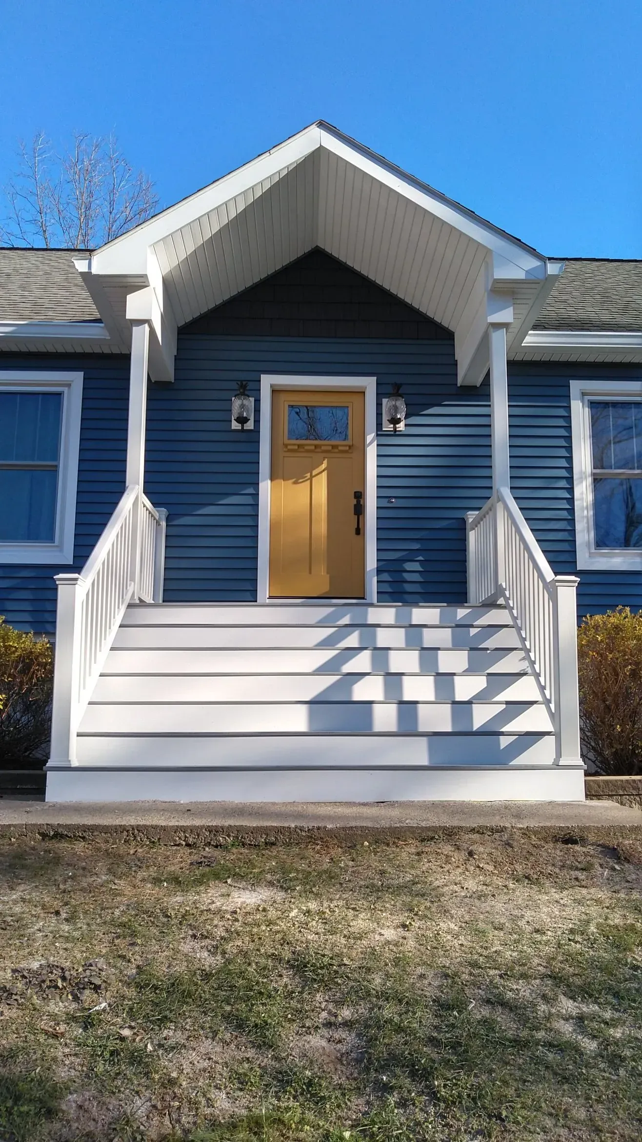 The front of a blue house with white stairs and a porch.