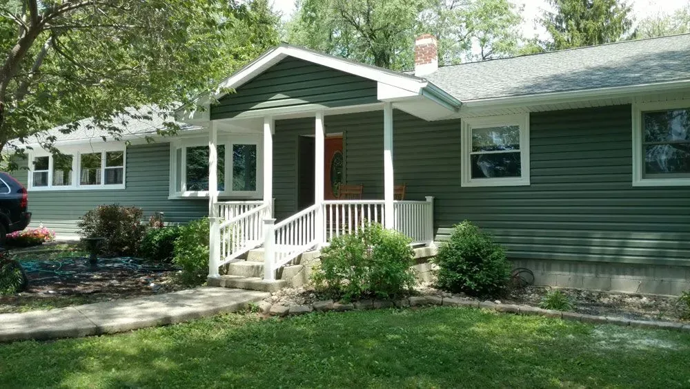 A house with a porch and a car parked in front of it