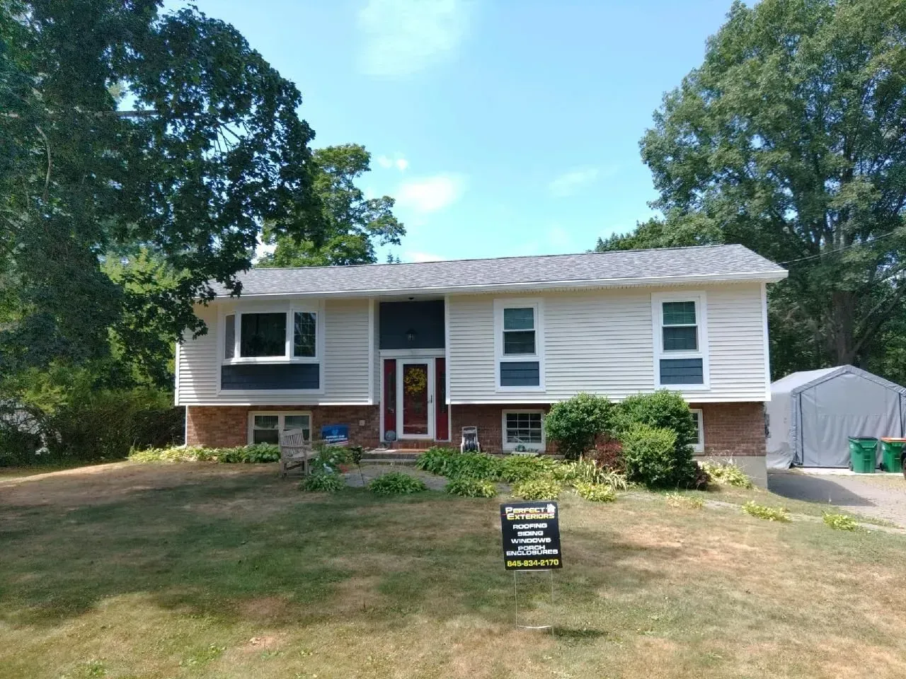 A white house with a red door and a sign in front of it.