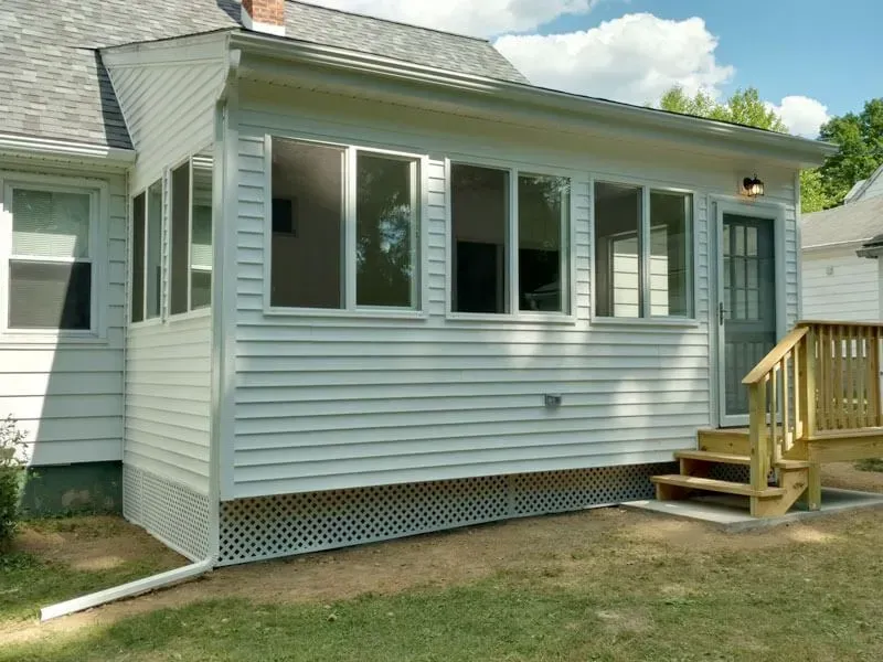 A white house with a screened in porch and stairs