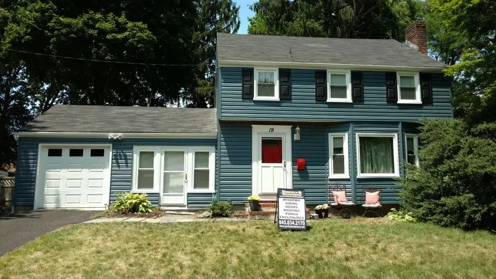 A blue house with a for sale sign in front of it