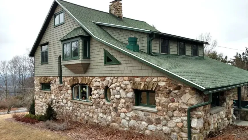 A large stone house with a green roof and a chimney.