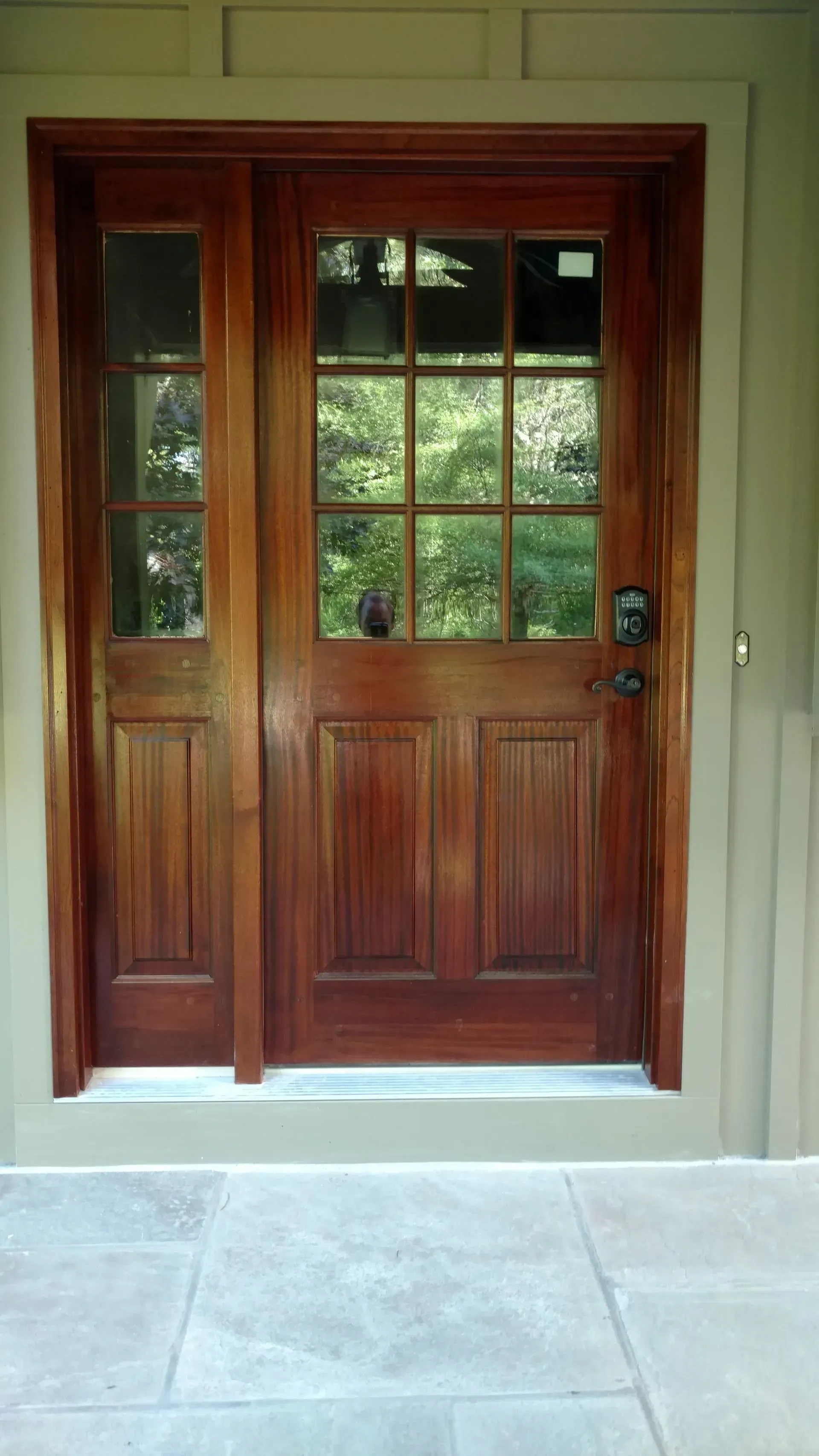 A wooden door with a lot of windows is sitting on a concrete floor.