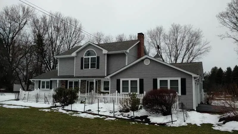 A house with snow on the ground and trees in the background