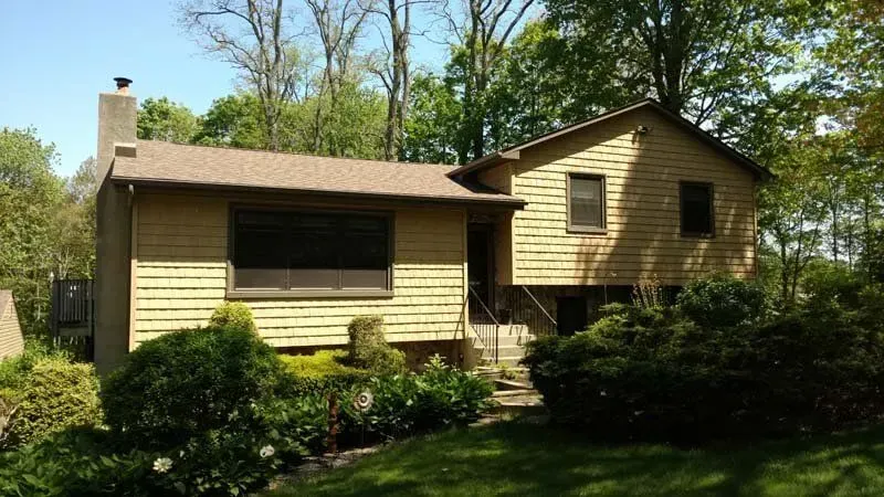 A house with a brown roof is surrounded by trees and bushes
