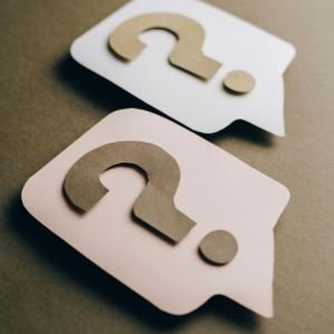 Two speech bubbles with question marks, one white and one light pink, arranged against a dark brown background.