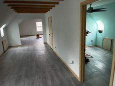 Interior of a newly renovated room with gray flooring, white walls, and a teal room visible through a doorway.
