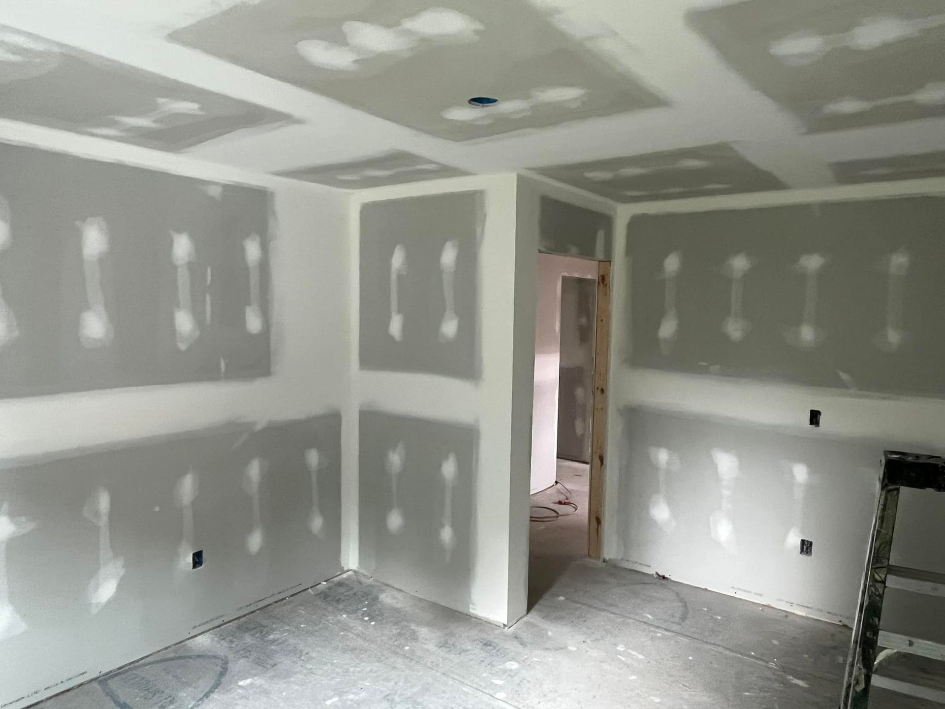 Room with drywall installed on walls and ceiling, unfinished, ready for mudding and taping.
