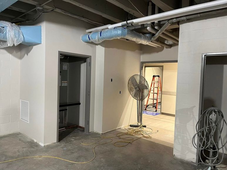 Basement renovation with unfinished walls, ductwork, and a fan.