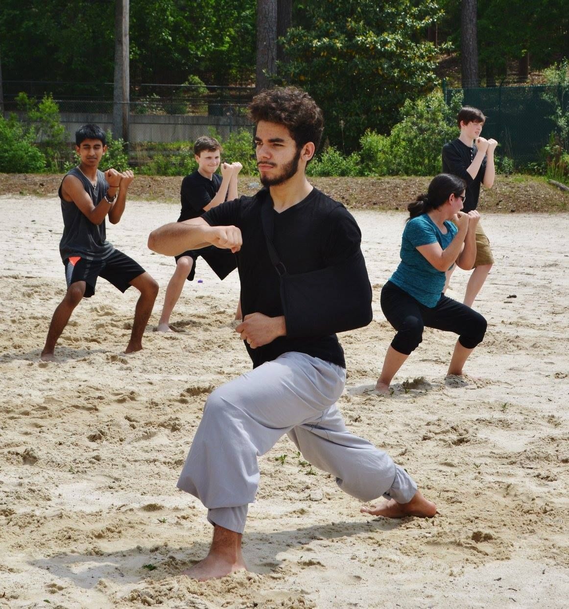 a group of people are practicing martial arts in the sand
