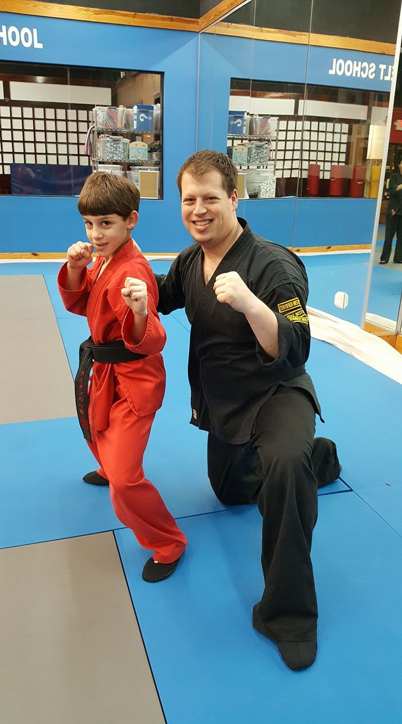 a man and a boy are posing for a picture in a martial arts gym .