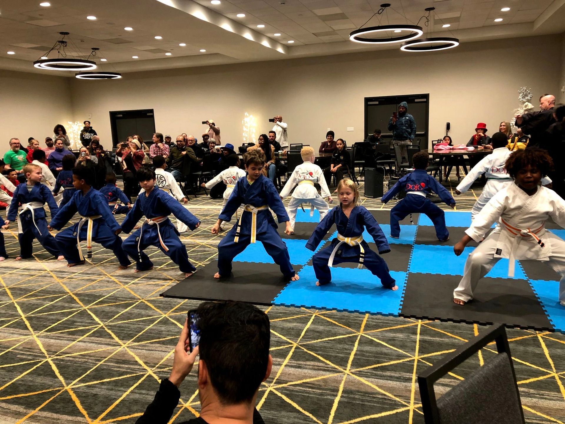 a group of children are practicing martial arts in a large room .
