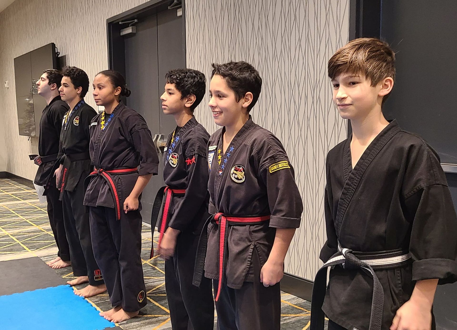 a group of young boys in karate uniforms are standing in a line .