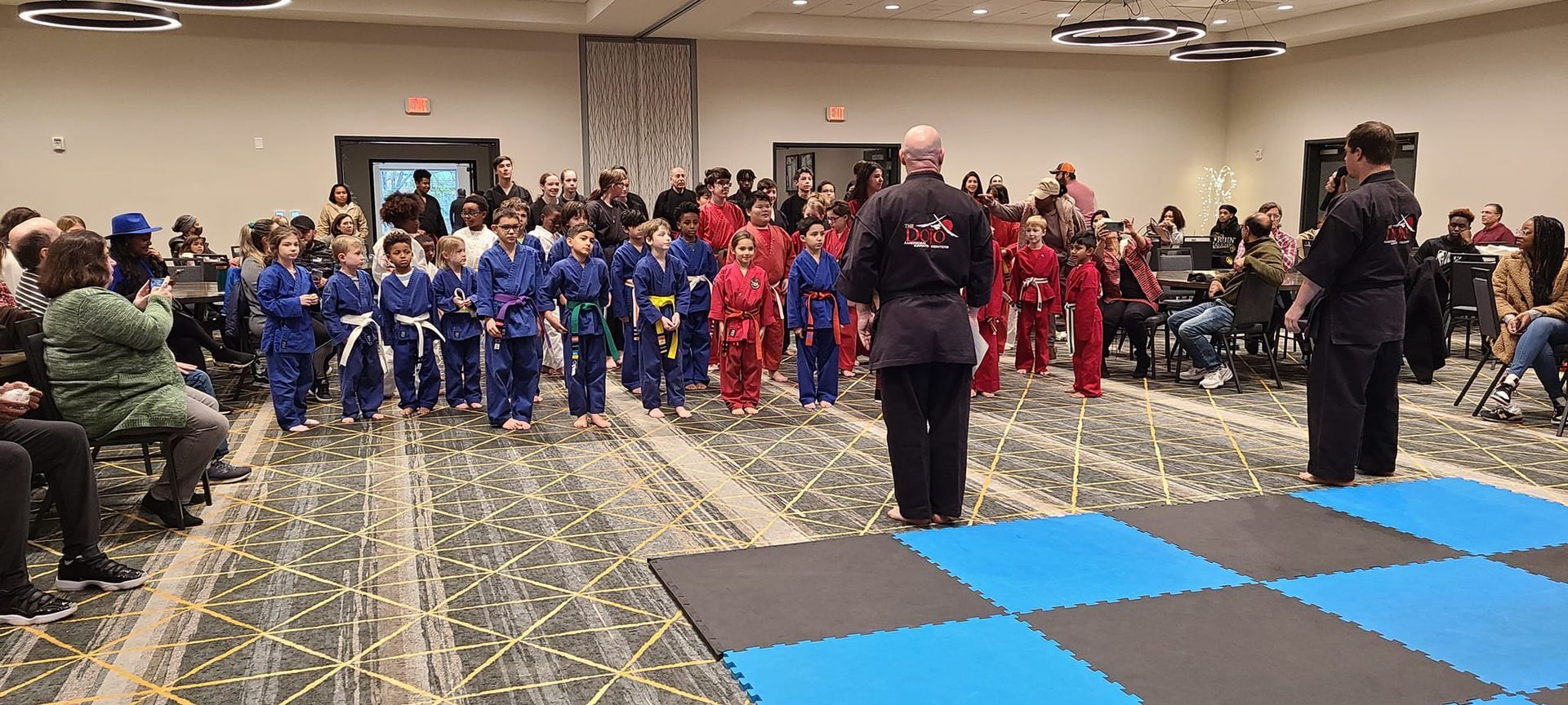 a group of people in karate uniforms are standing in a room .