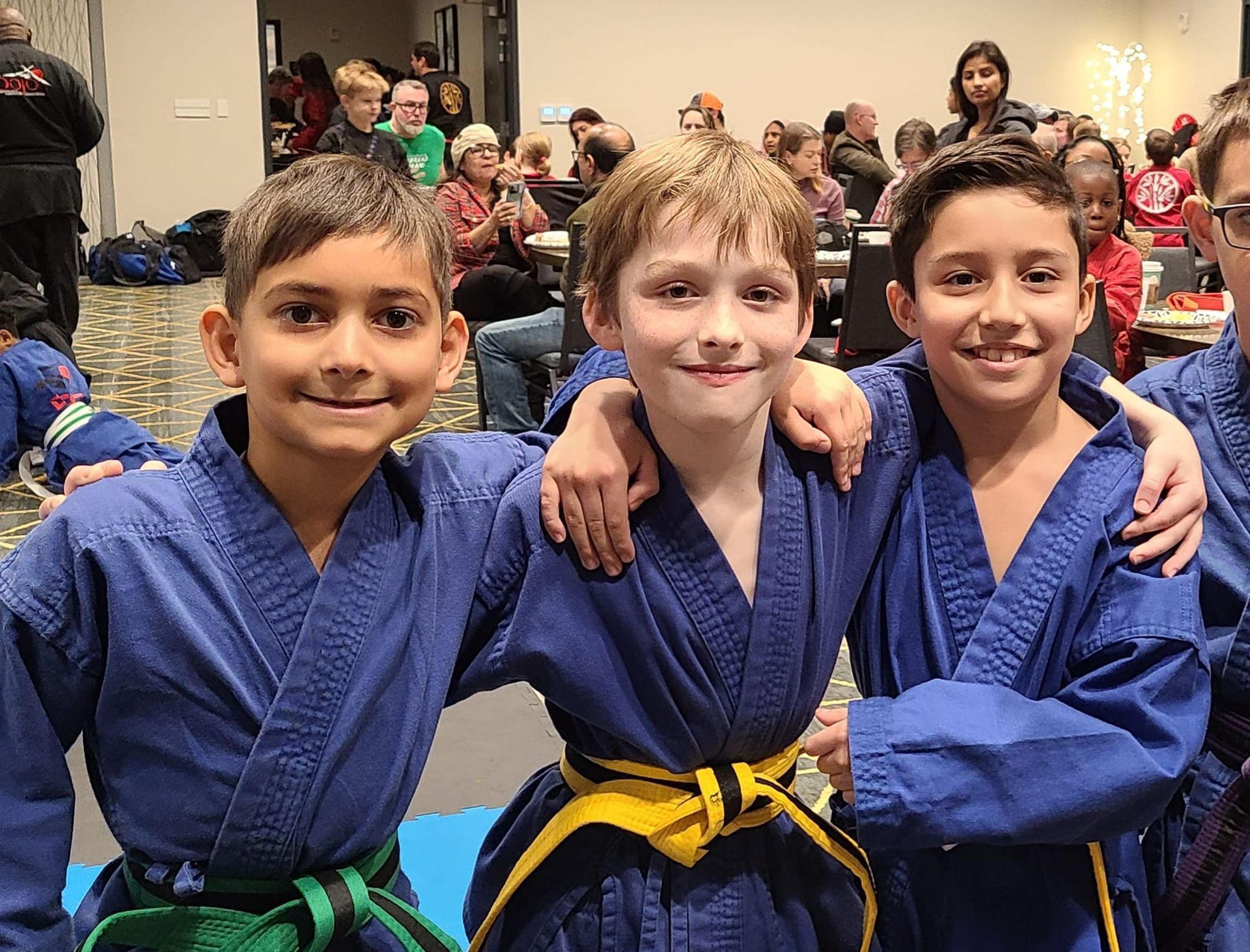 three young boys in karate uniforms are posing for a picture .