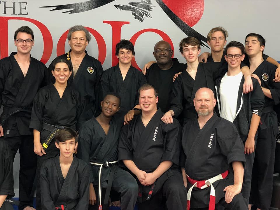 a group of people posing for a picture in front of a sign that says the dojo