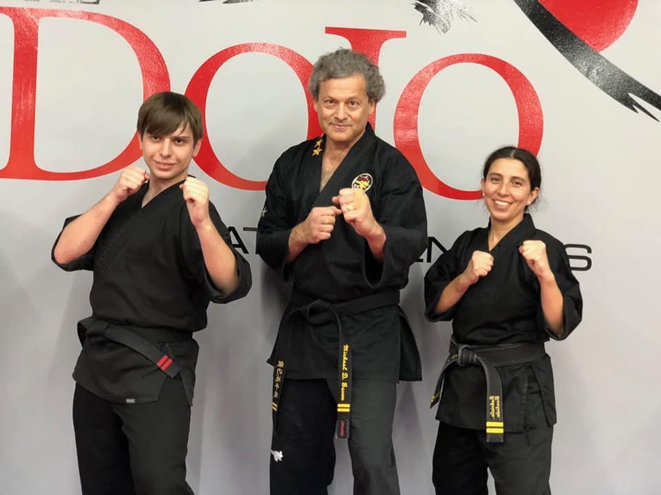 a man and two women are posing for a picture in front of a sign that says dojo