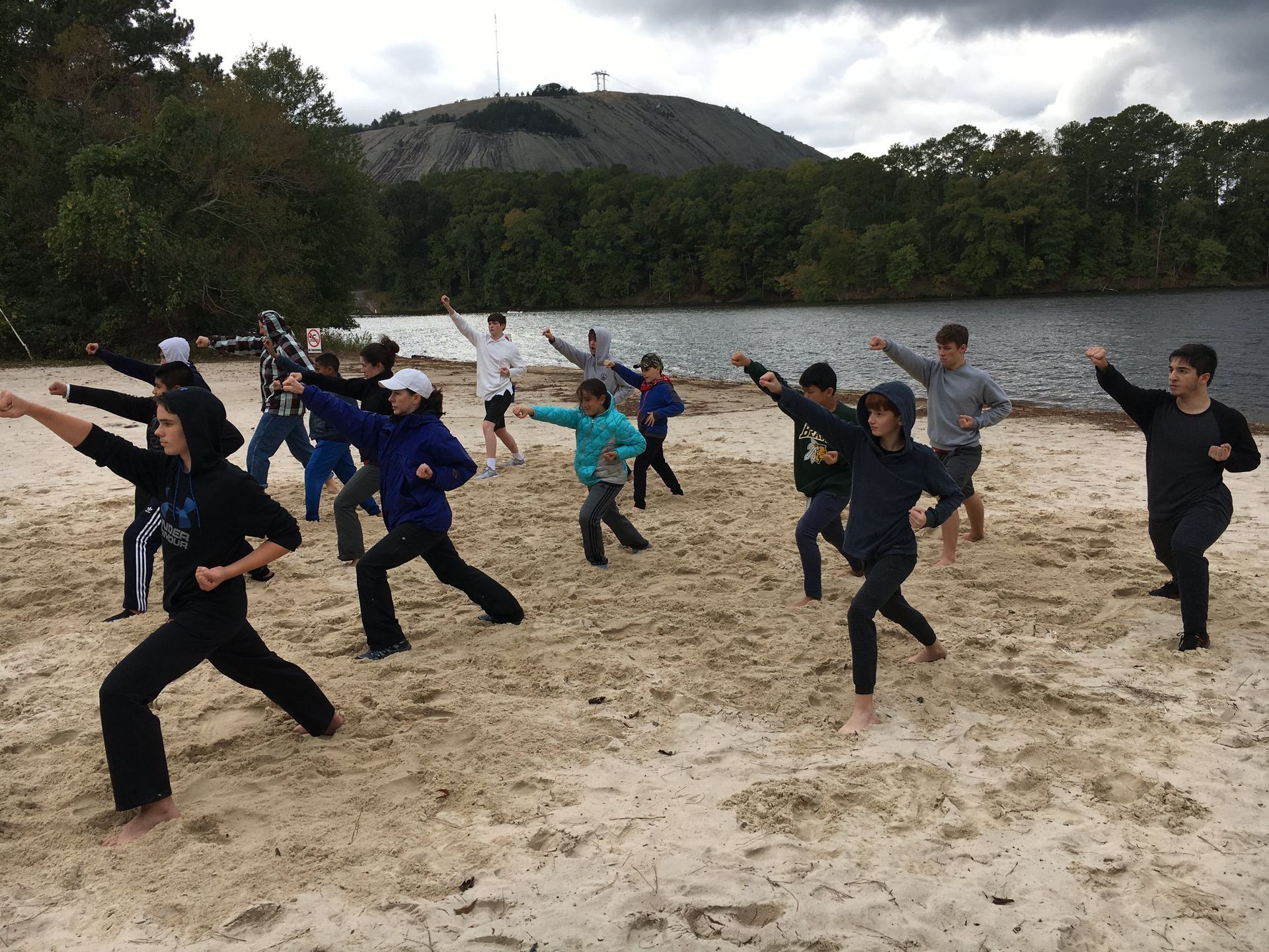 a group of people are practicing martial arts on a beach .