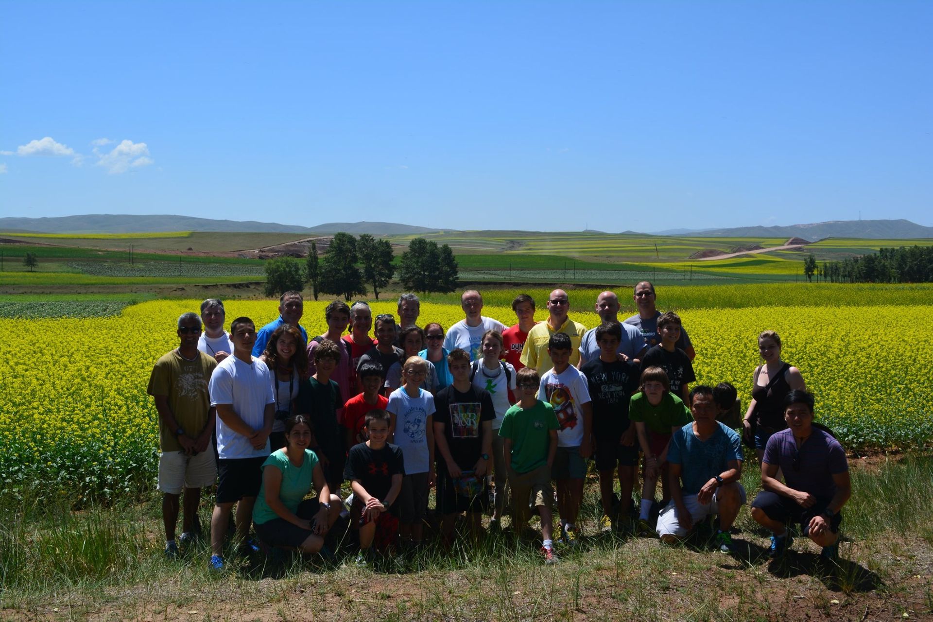 a group of people are posing for a picture in front of a field of yellow flowers .