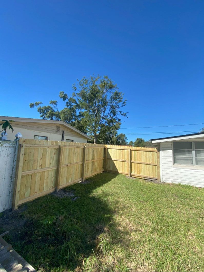 A wooden fence is in the backyard of a house.