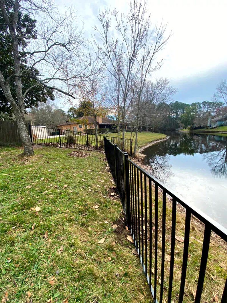 A wrought iron fence surrounds a pond in a park.