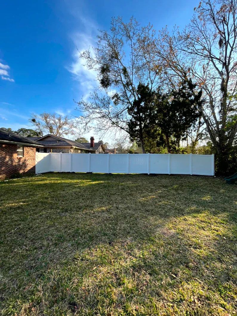 There is a white fence in the backyard of a house.