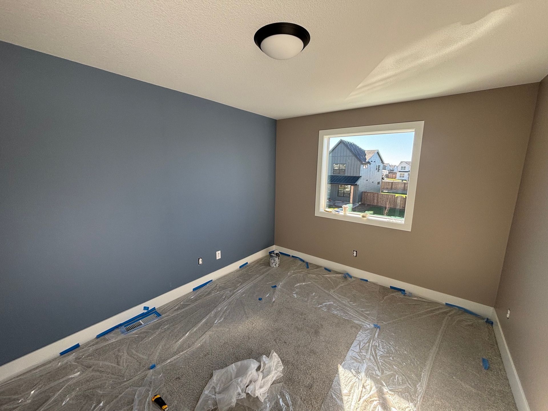 An empty room with a window and plastic covering the floor.