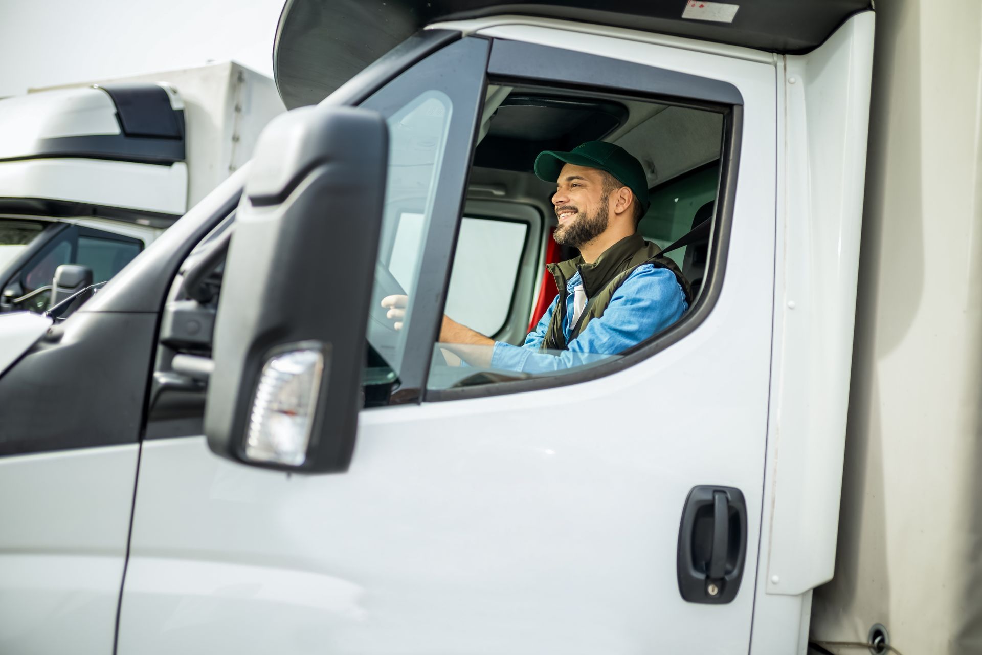 Smiling truck driver in a white cab.