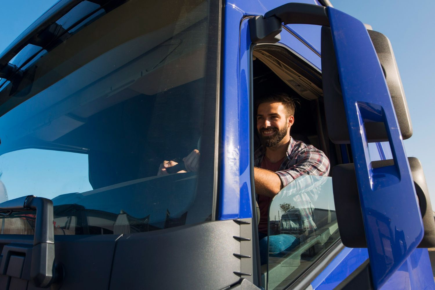 A man is sitting in the driver 's seat of a blue truck.