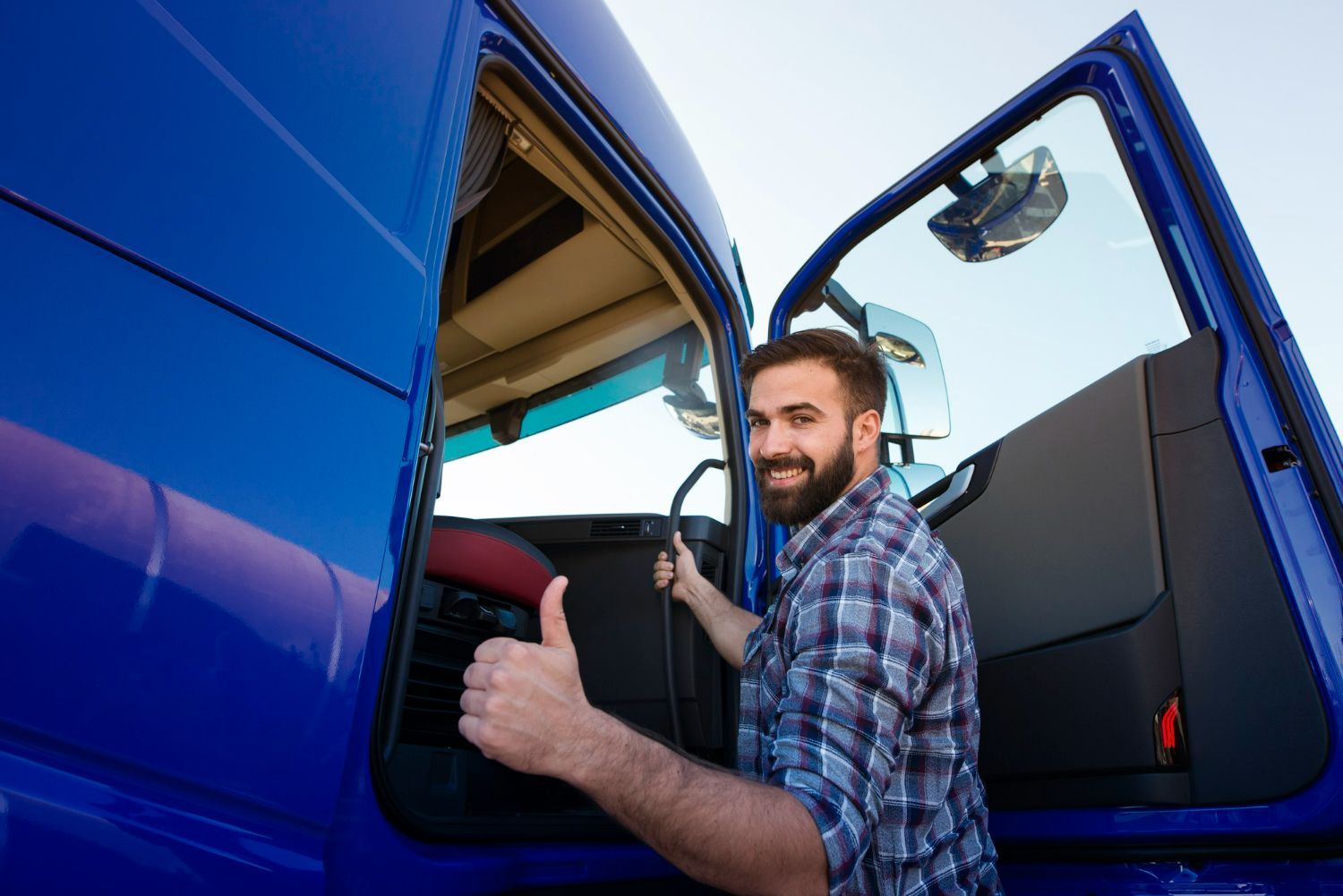 A man is getting out of a blue truck and giving a thumbs up.