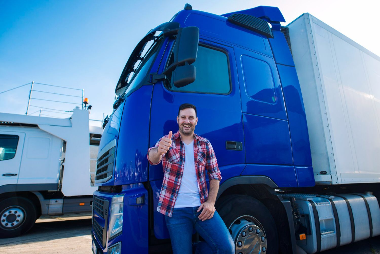 A man is standing next to a blue truck and giving a thumbs up.