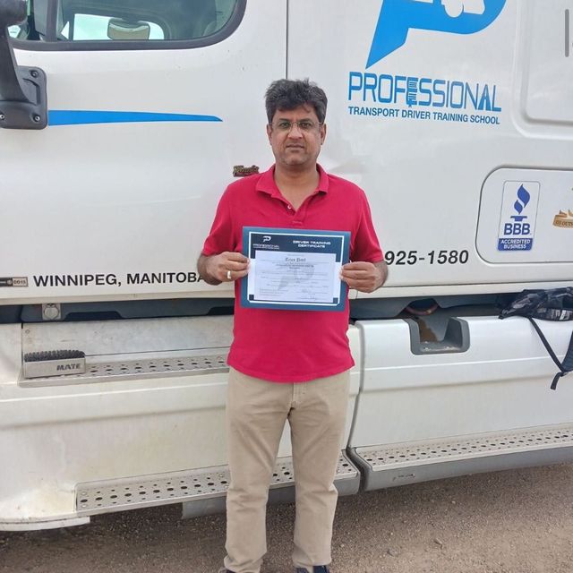 A man in a red shirt is standing in front of a professional truck