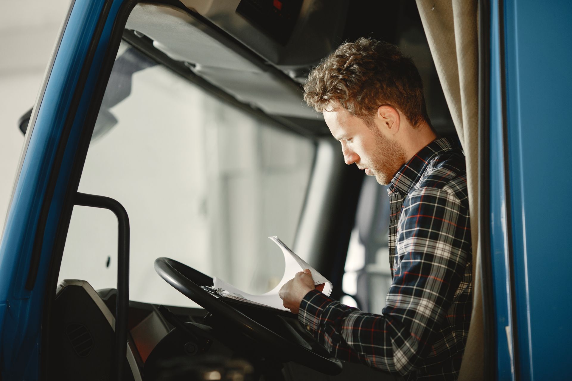 A man is sitting in the driver 's seat of a blue truck.