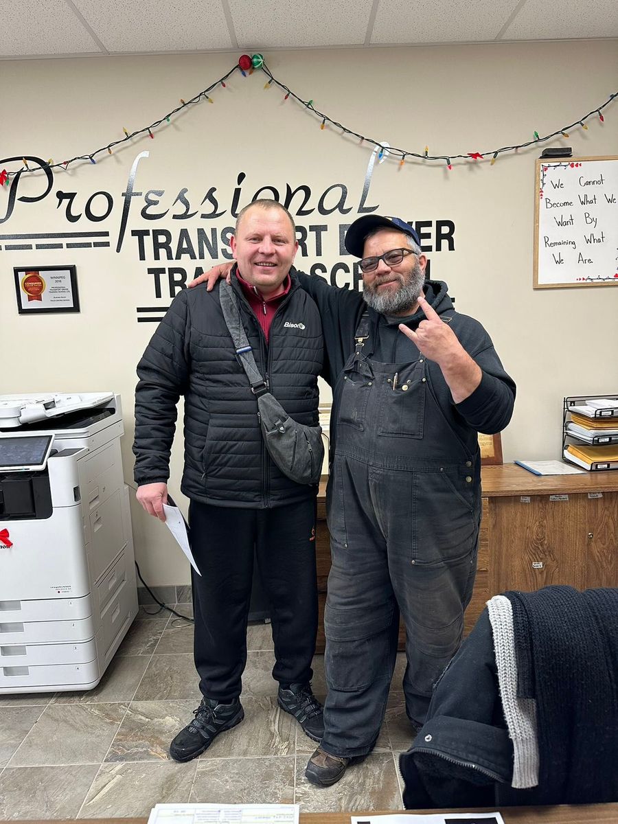 Two men are posing for a picture in front of a wall that says professional transport