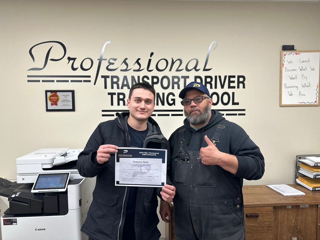 Two men are standing next to each other in front of a sign that says professional transport driver training school.