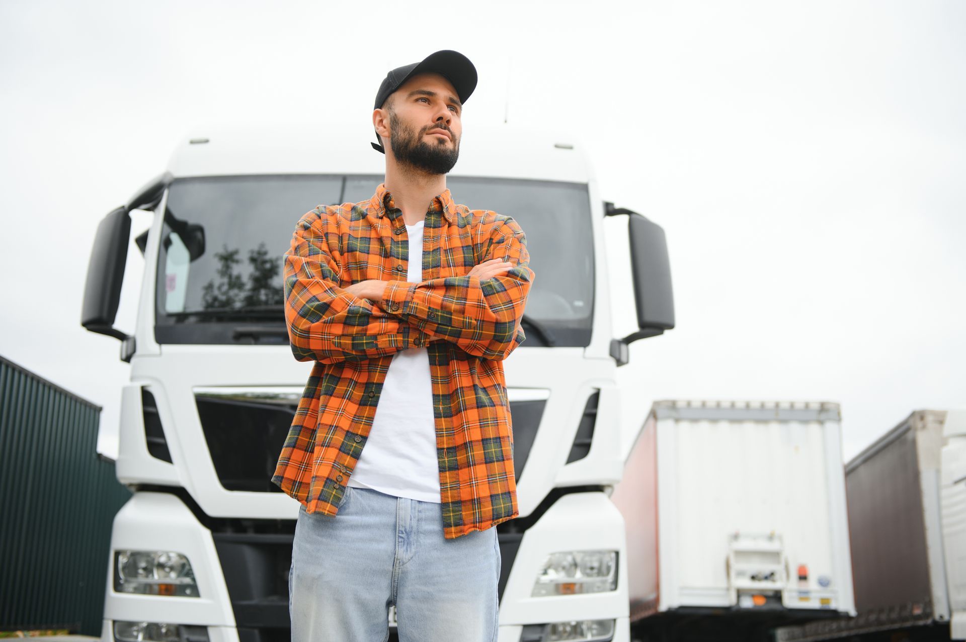 A man is standing in front of a truck with his arms crossed.