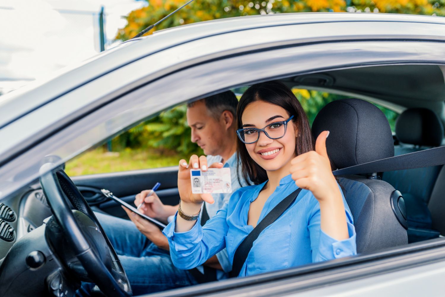 A woman is giving a thumbs up while sitting in a car.