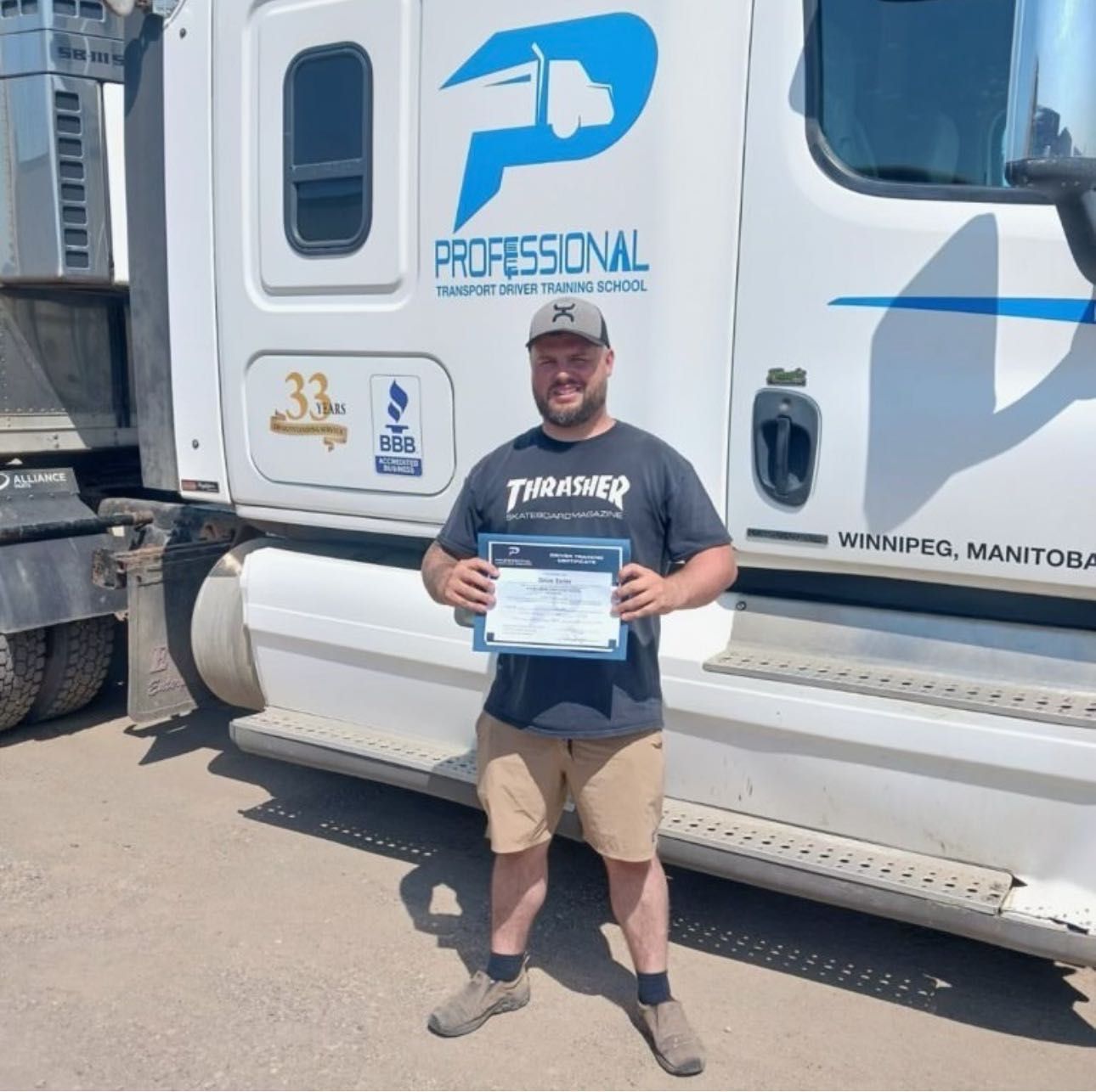 A man in a thrasher shirt is standing in front of a professional truck