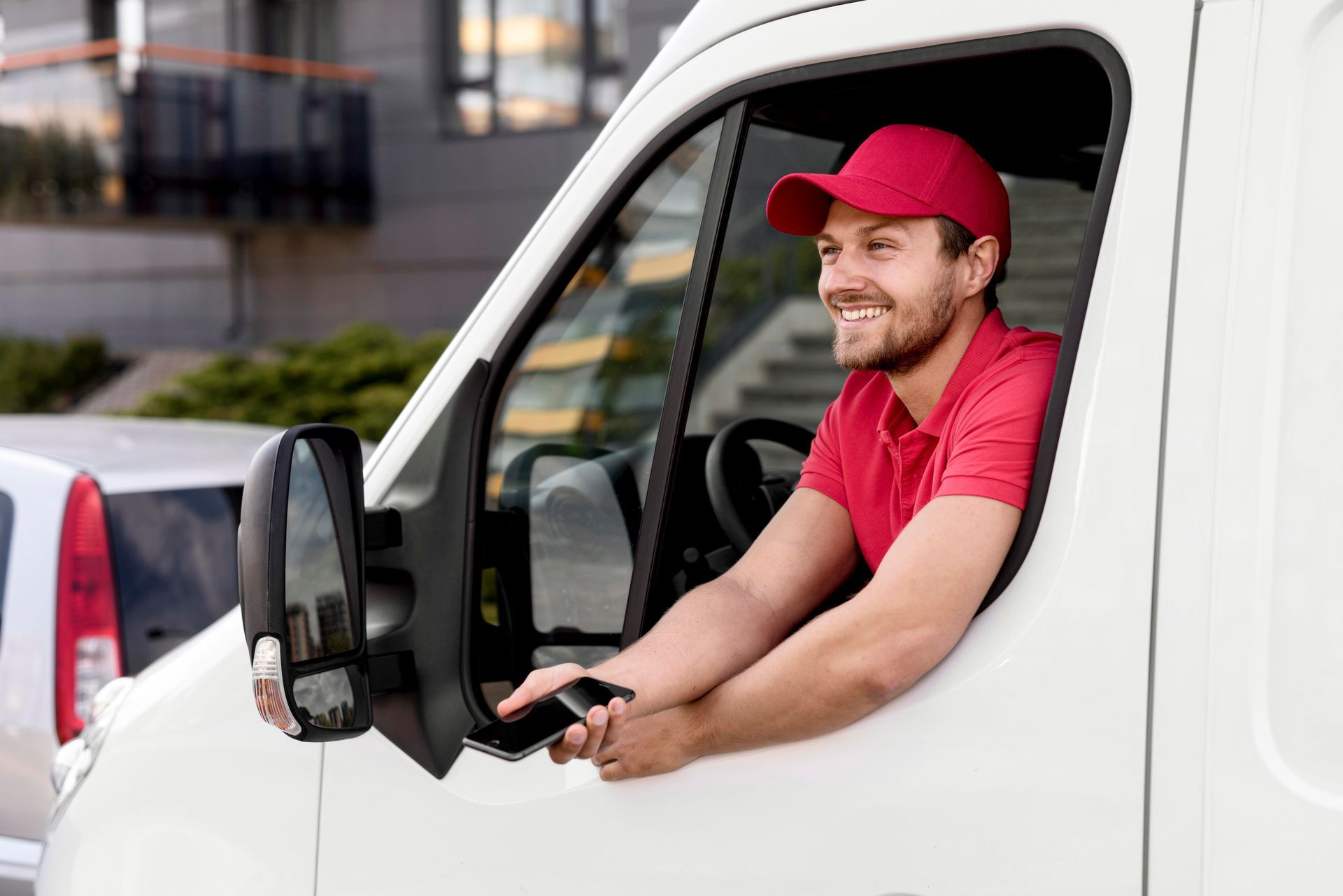 A delivery man is sitting in the driver 's seat of a white van.