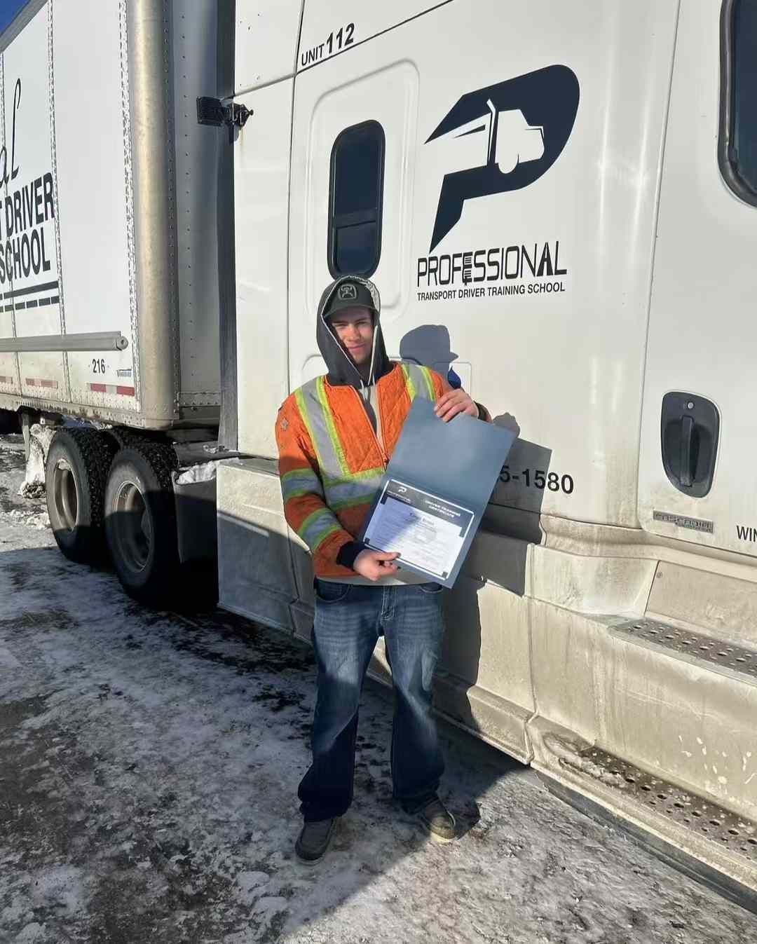 A man is standing in front of a semi truck holding a clipboard.
