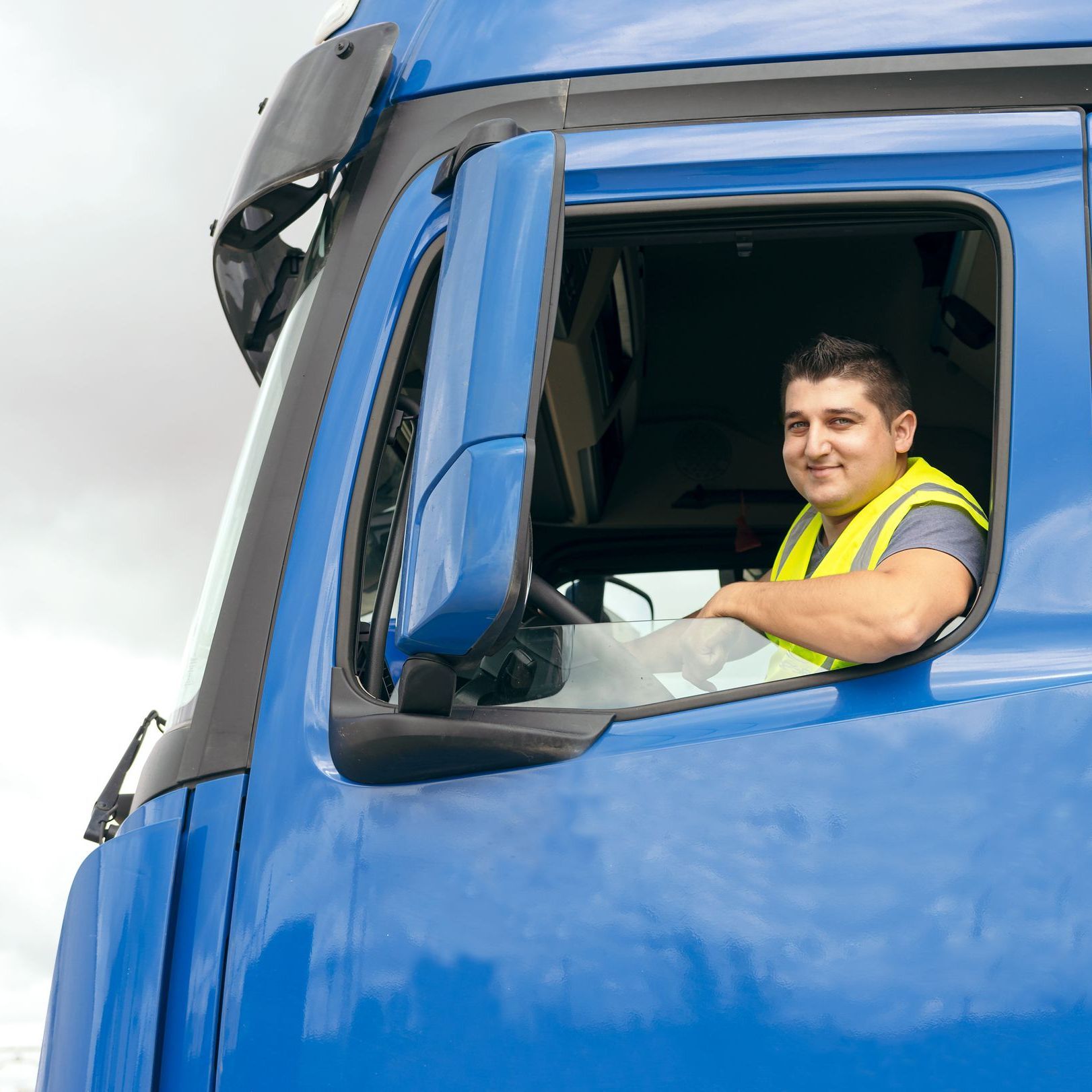 a man is sitting in the driver 's seat of a blue truck .